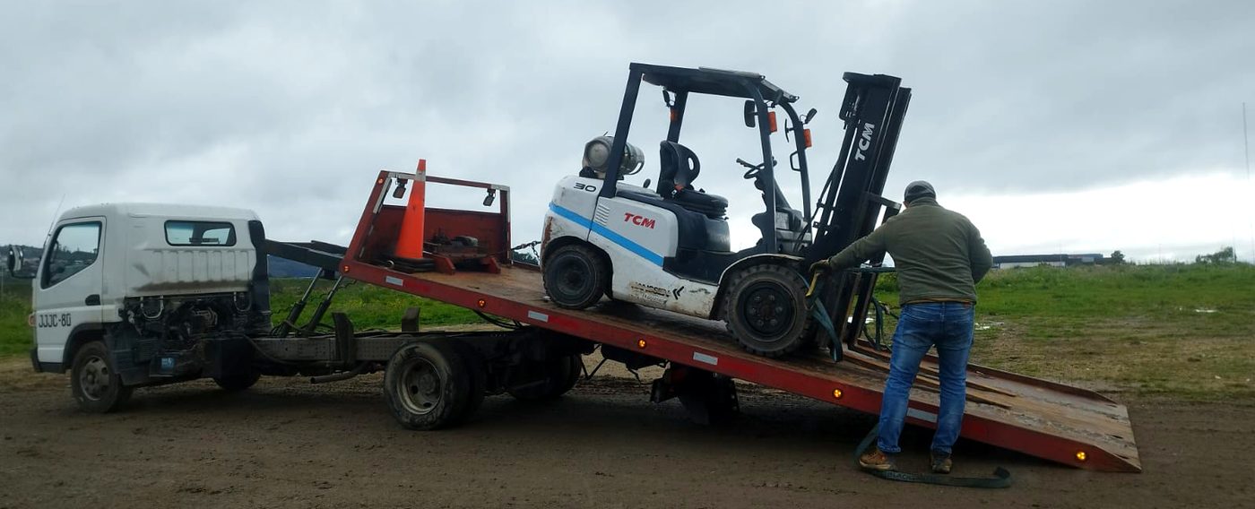 Un operario de LaraMaq amarrando la grúa horquilla TCM sobre la rampla del camión, antes de salir a faena.